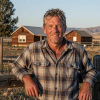 Portrait of Daniel, 57, a former builder from Boise Idaho, smiling beside a wooden fence